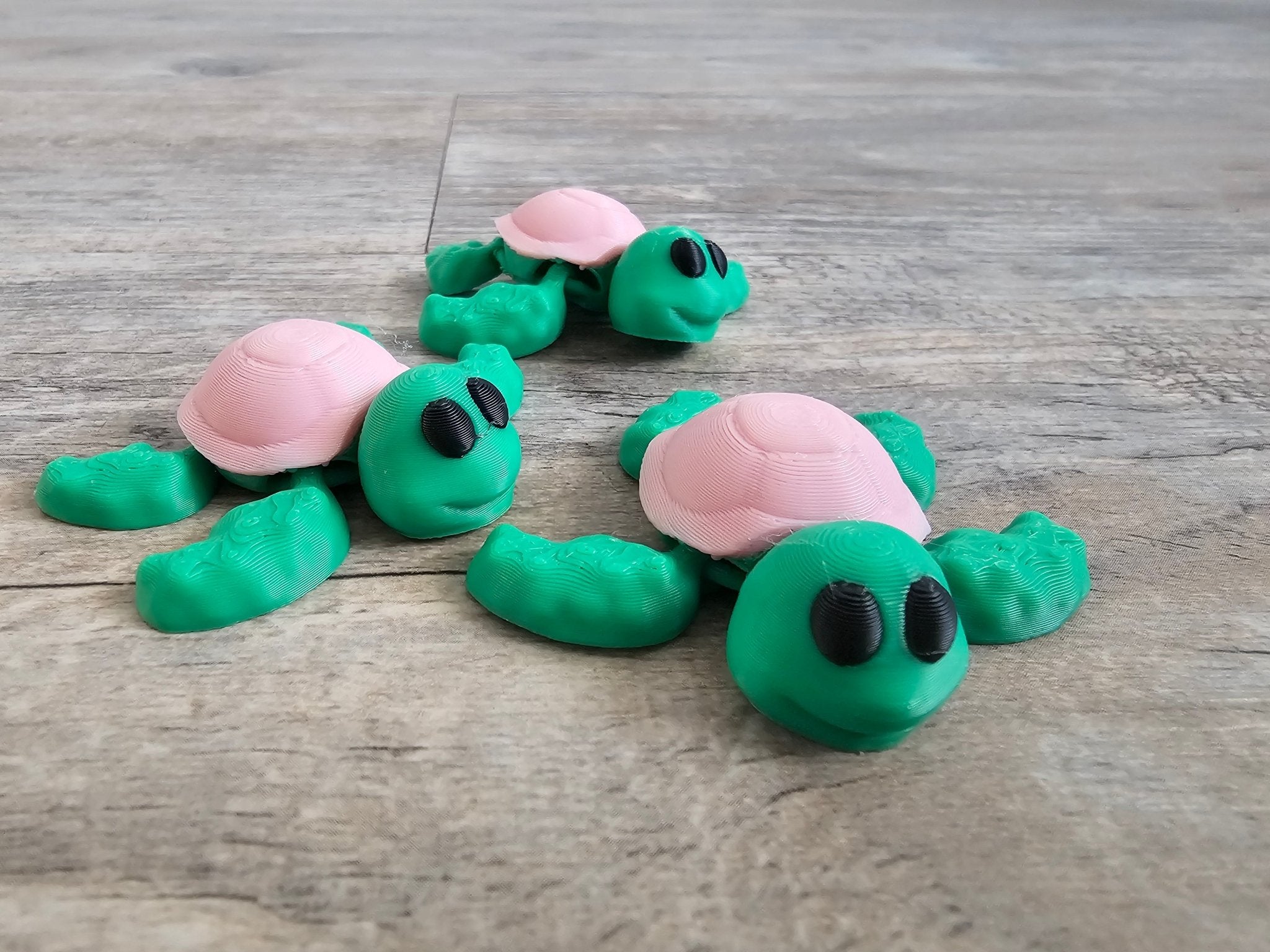 3D printed mini turtles from Main Street Collective. Cute pink and green fidget toys, perfect for kids and desk pets.