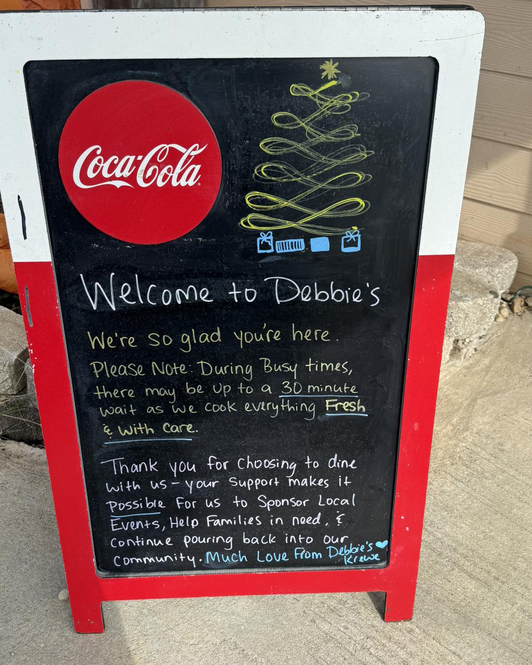 Debbie's restaurant sign: Welcome message, Coca-Cola, holiday tree. Fresh food, local community support.