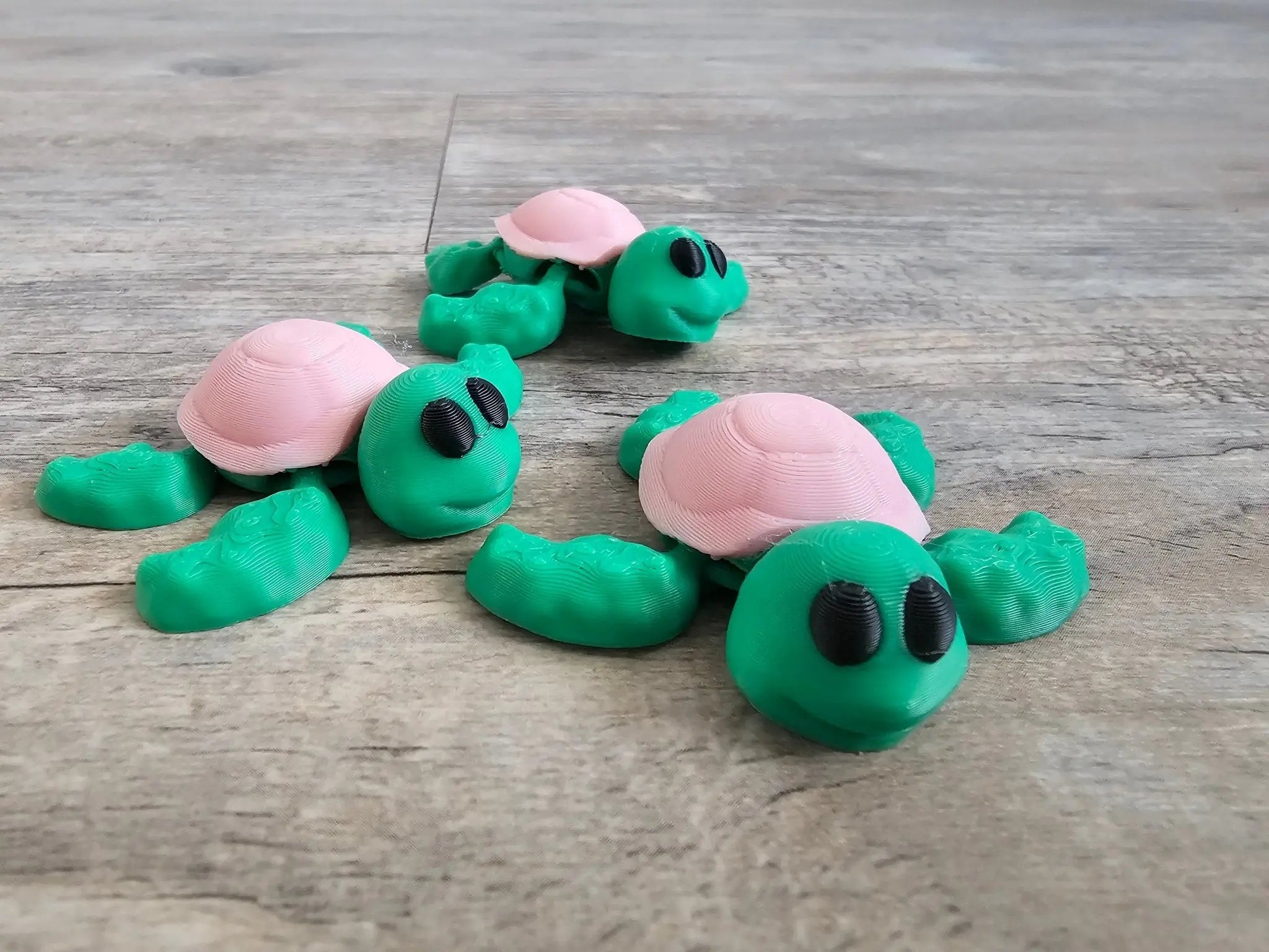 3D printed mini turtles from Main Street Collective. Cute pink and green fidget toys, perfect for kids and desk pets.