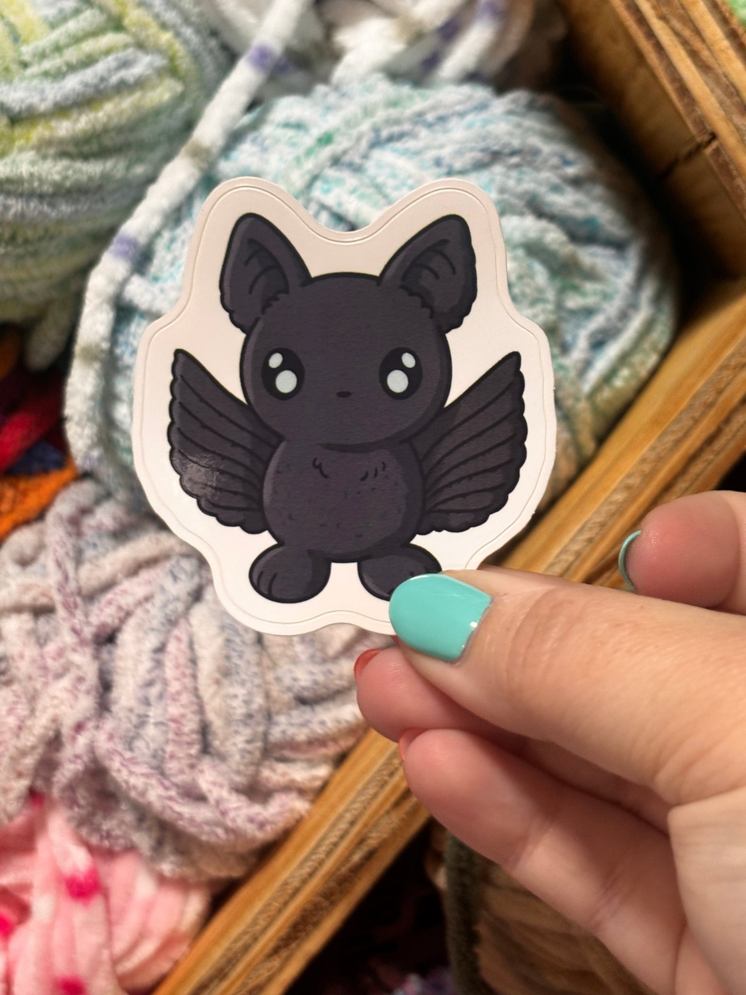 Bailey the Bat Sticker: Cute bat sticker held in hand with colorful yarn. Main Street Collective vinyl decal.