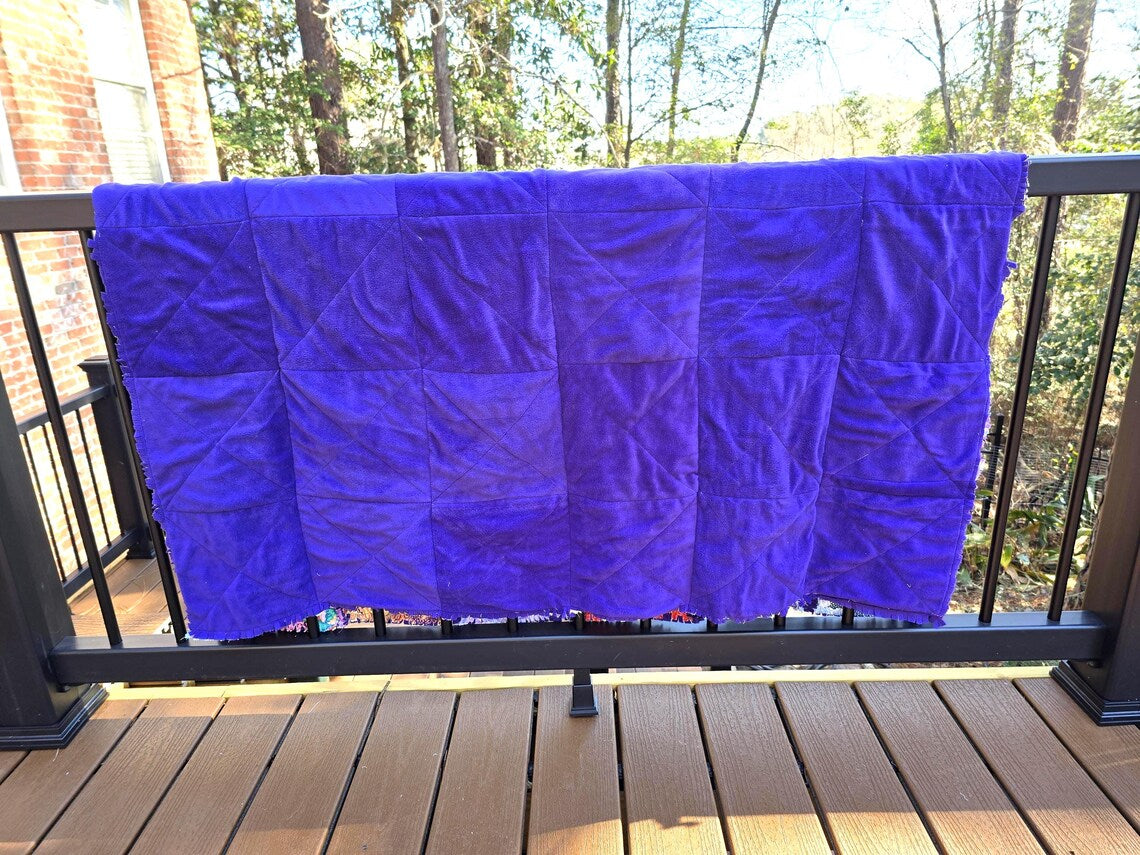Purple rag quilt on deck railing. Handmade quilt with square pattern and fleece backing.