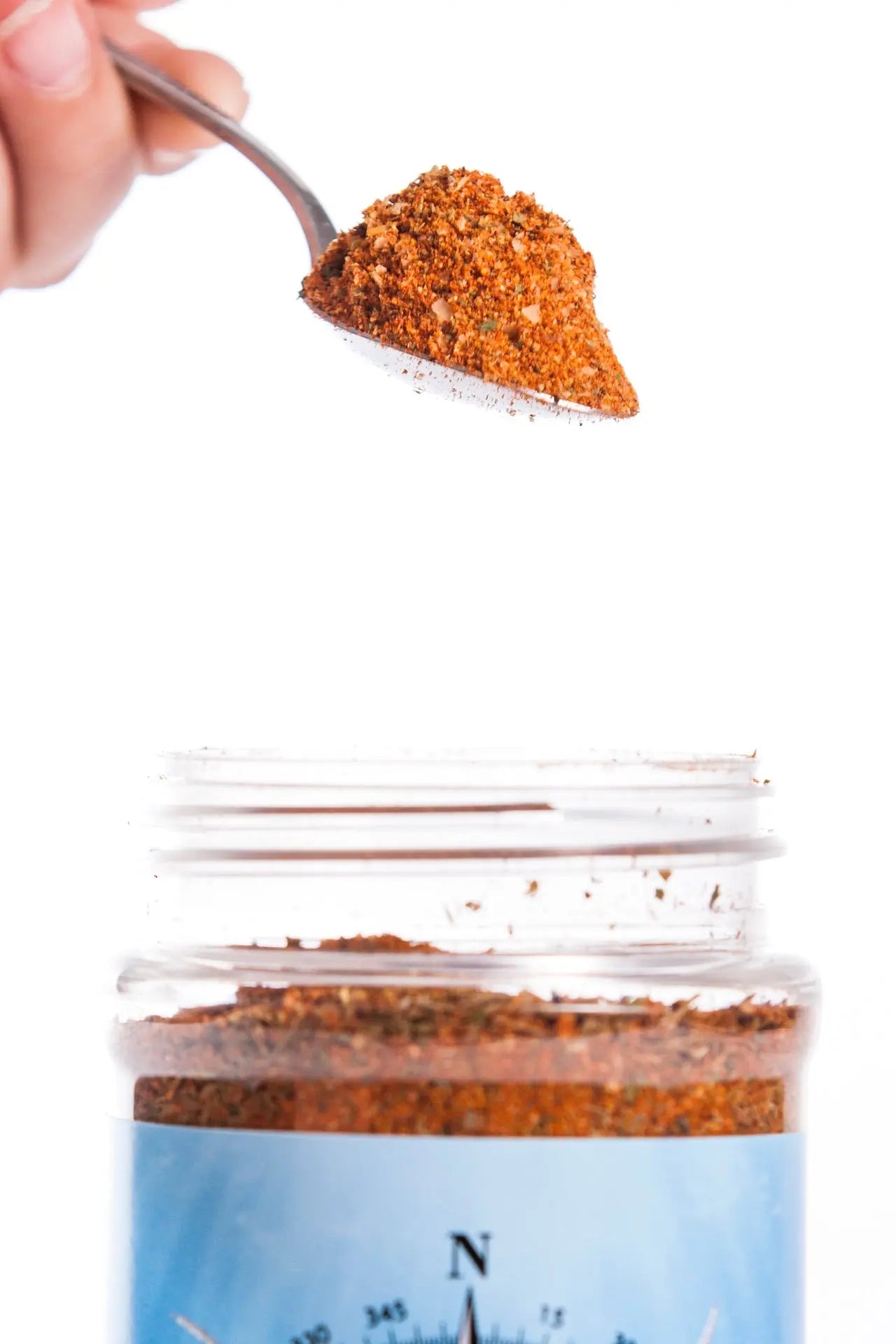 Creole Spice Blend: Spoonful of seasoning being poured into a jar. Main Street Collective Creole Blend. Enhance your dishes.