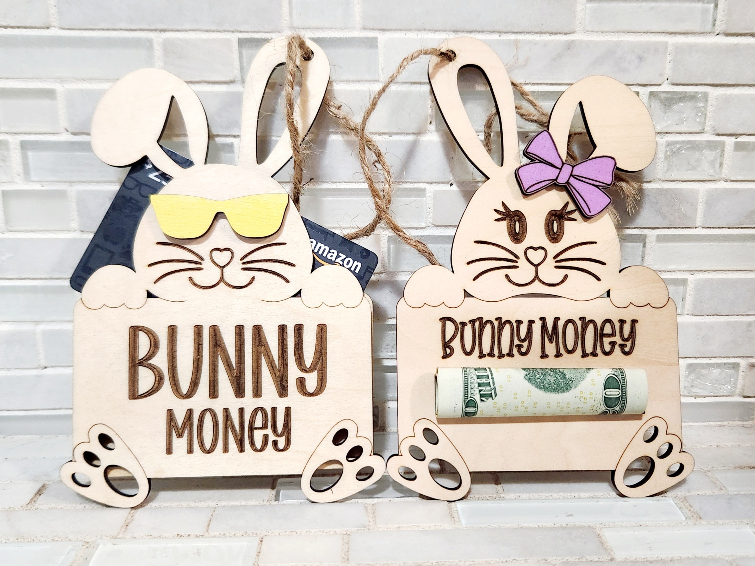 Two wooden Easter bunny money holders: one with sunglasses and a gift card, the other with a bow and cash.