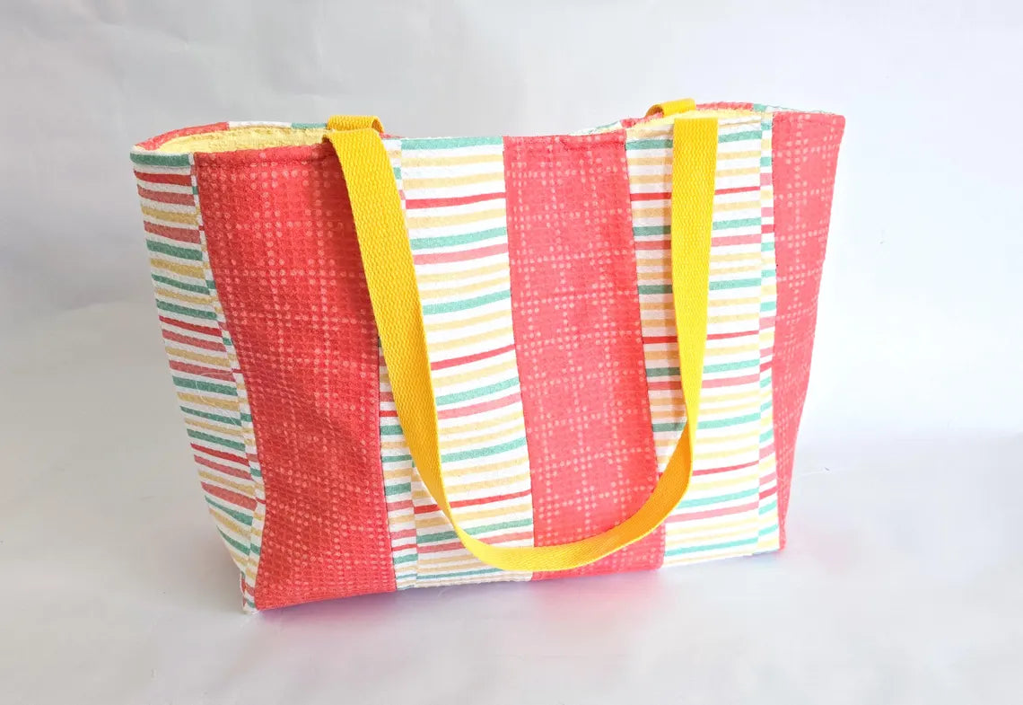 Terry cloth tote bag with coral, yellow straps, and pastel stripes for beach or pool use.