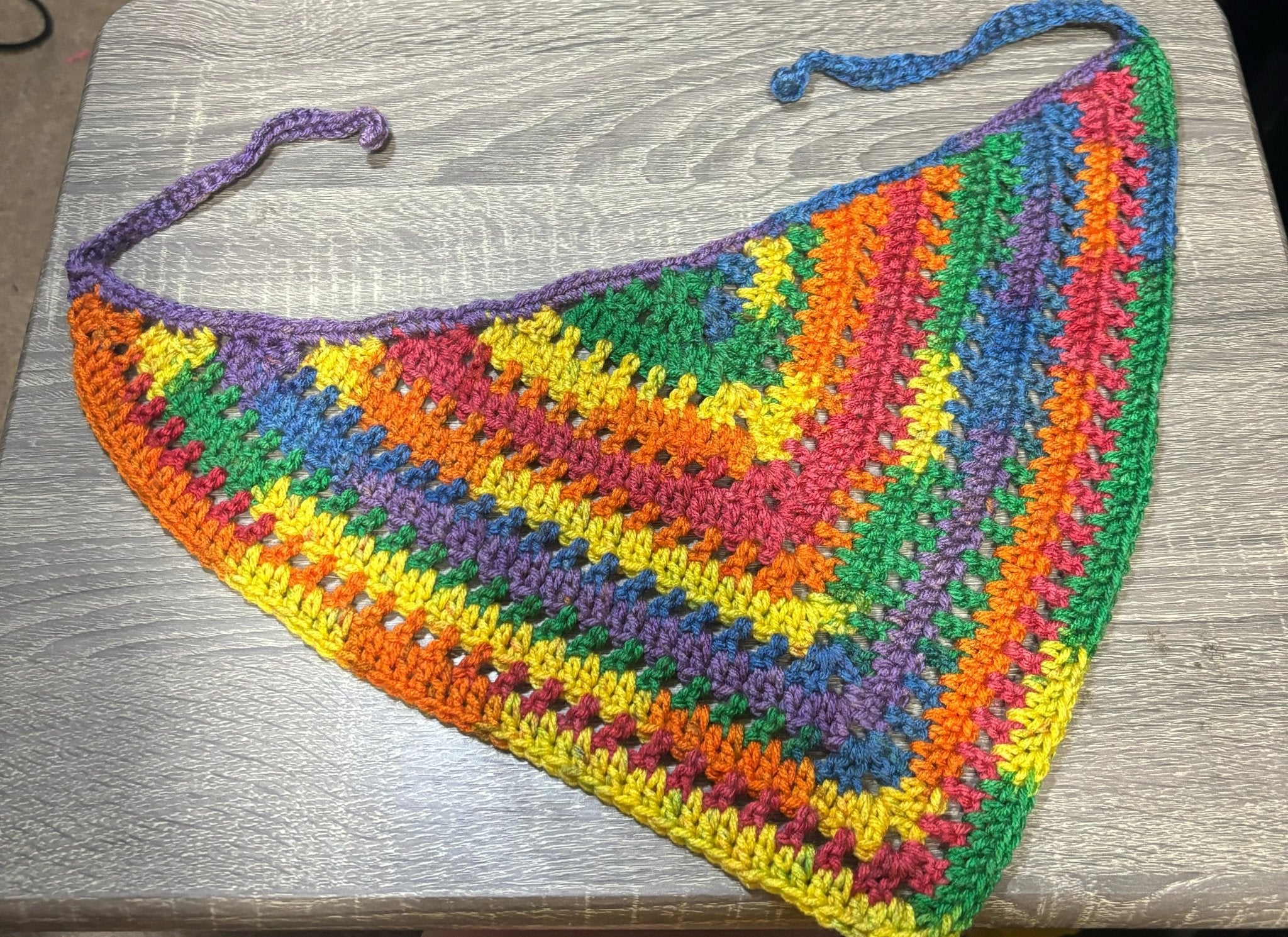 Handmade crocheted bandana featuring the rainbow pride colors: red, orange, yellow, green, blue, and purple.
