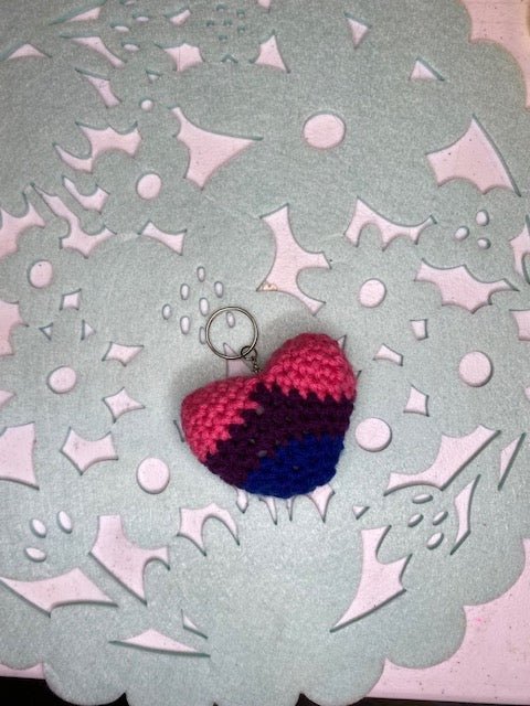 Handmade crocheted heart keychain in bisexual pride colors: pink, purple, and blue.

