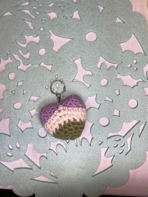 Handmade crocheted heart keychain in genderqueer pride colors: lavender, white, and green.
