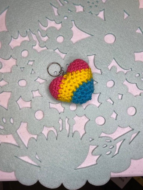 Handmade crocheted heart keychain in pansexual pride colors: pink, yellow, and blue.