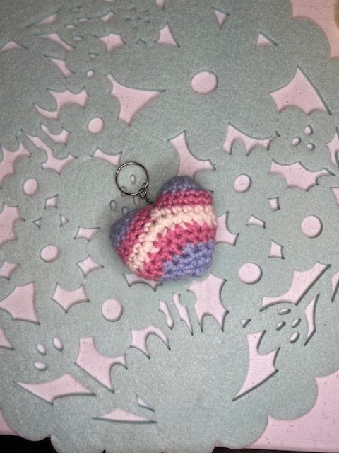 Handmade crocheted heart keychain in transgender pride colors: light blue, pink, and white.