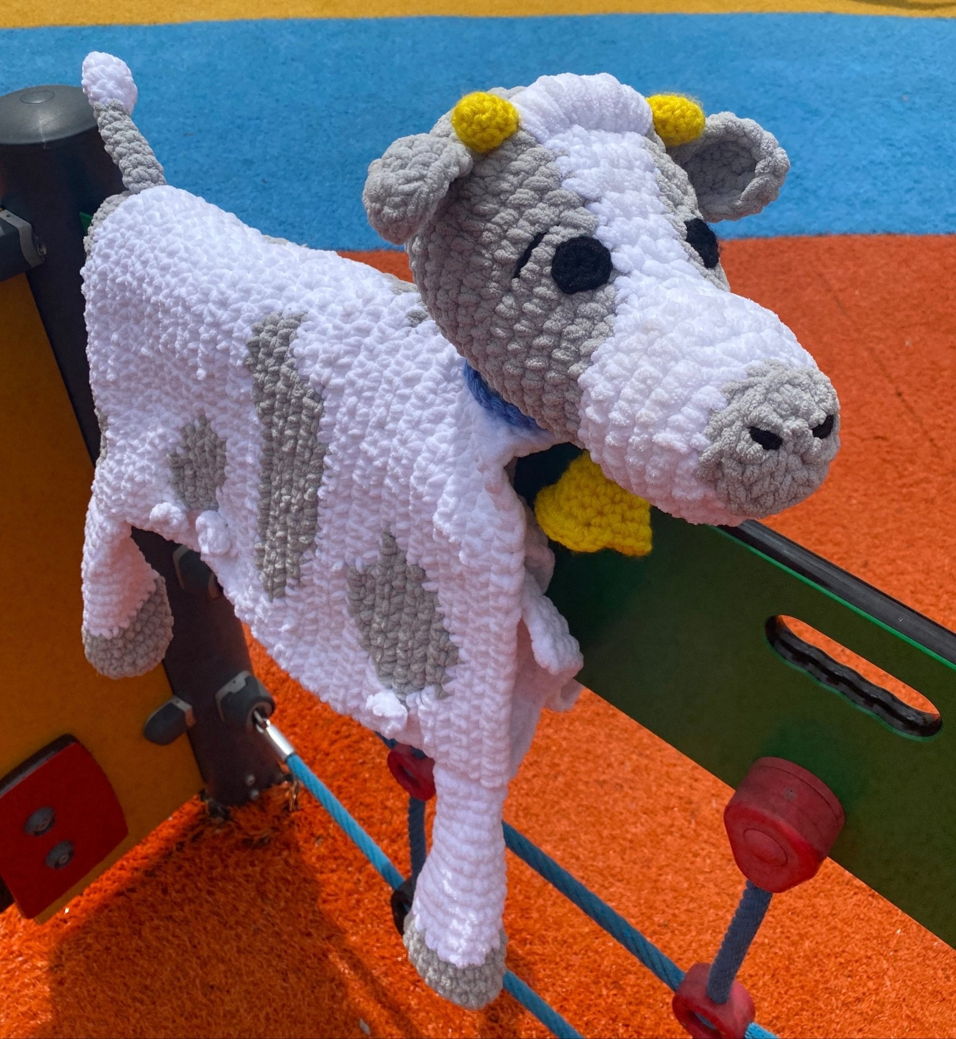 Handmade Crochet Cow Blanket Toy: Cuddly, Soft, Unique Baby Gift. Crochet details, cute toy on playground equipment.