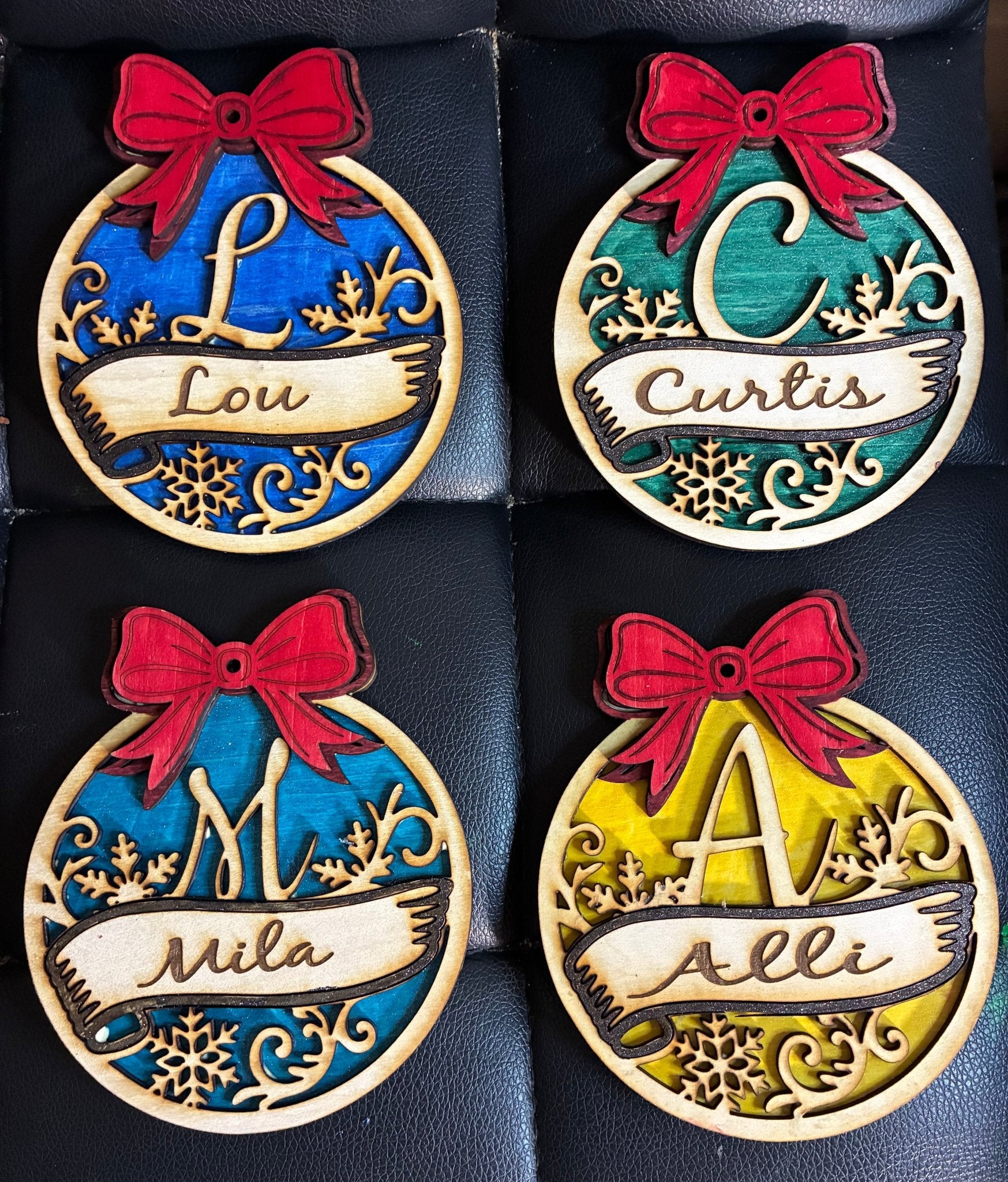 Personalized Christmas Ornaments: Lou, Curtis, Mila, Alli. Laser-cut wooden decorations with names, bows. Main Street Collective