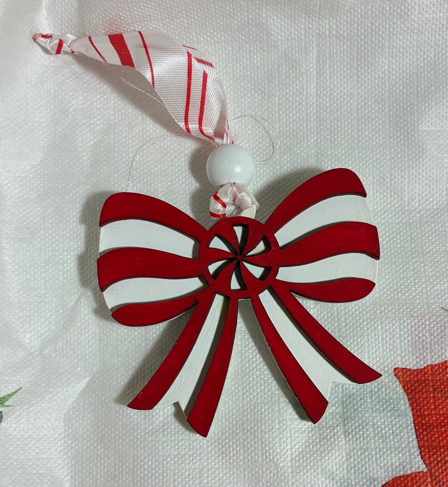 Hand-painted red and white wooden Christmas bow ornament by Main Street Collective.