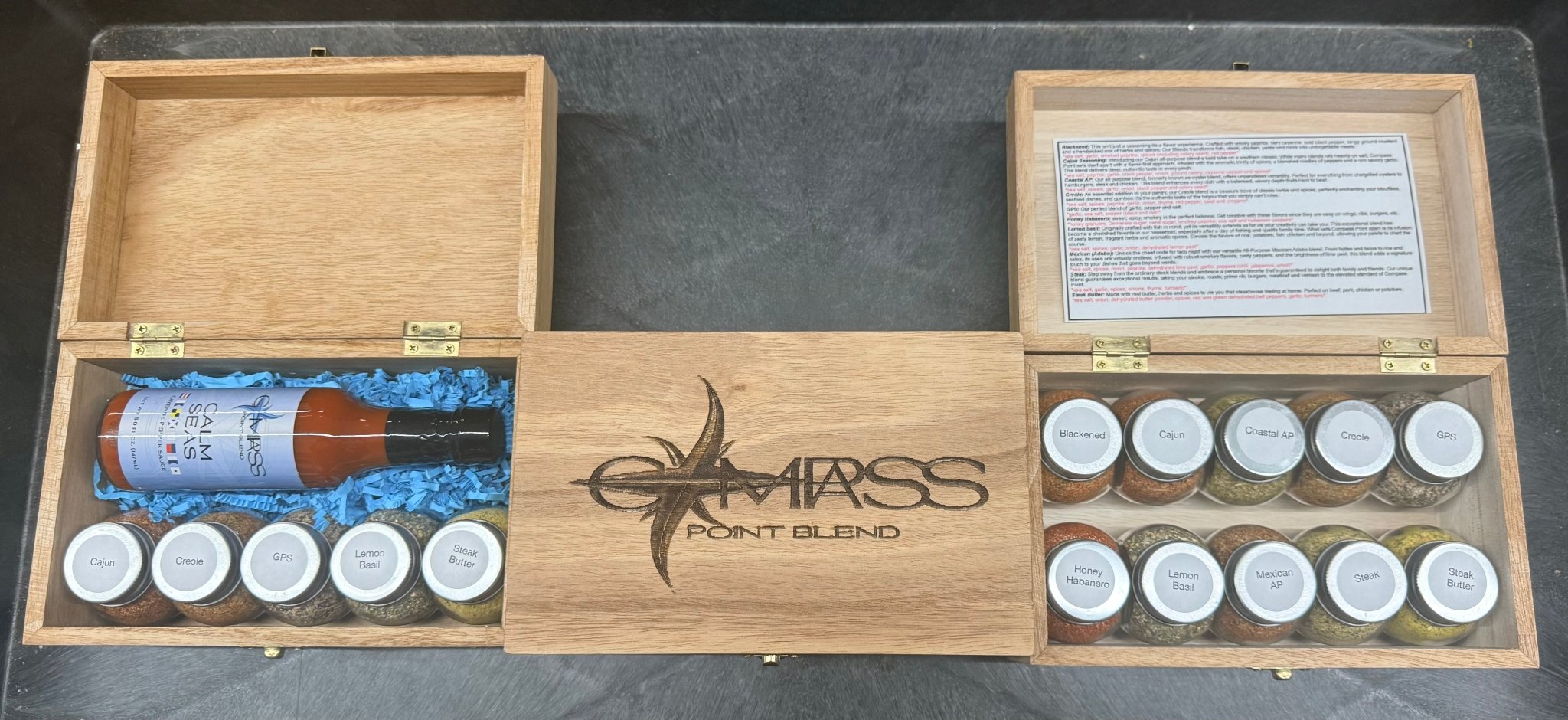 Compass Point Blends wooden box with hot sauce, spices like Cajun, Creole, GPS, & Steak Butter.