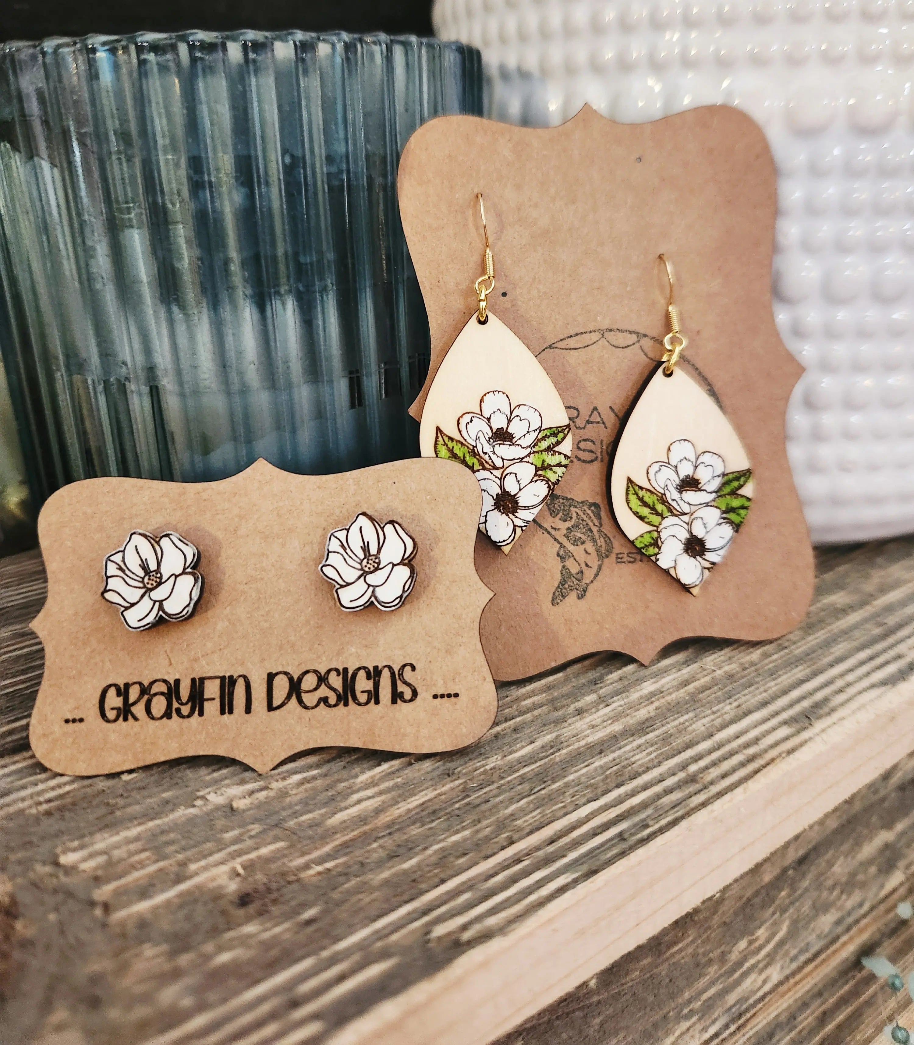Magnolia earrings: wooden dangle and stud earrings with white flower design by Grayfin Designs on a wooden surface.