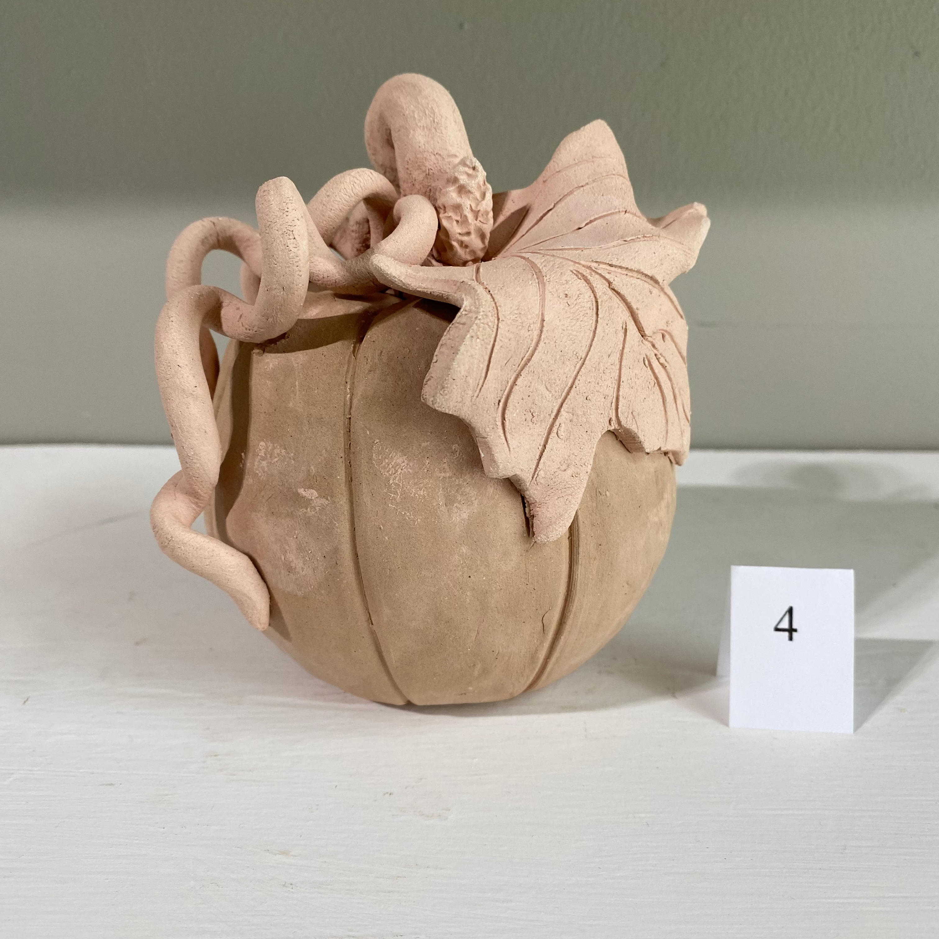 Handmade clay pumpkin with leaf and vine details, perfect for fall decor. Pottery from Main Street Collective.