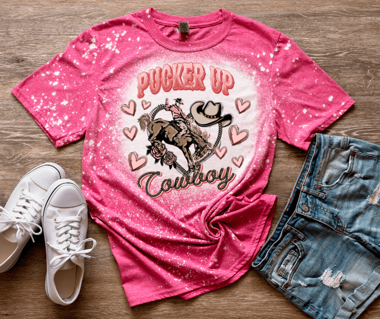 Pink "Pucker Up Cowboy" Valentine's T-shirt with Cowboy Riding a Horse, Hearts, and bleached design. Main Street Collective.