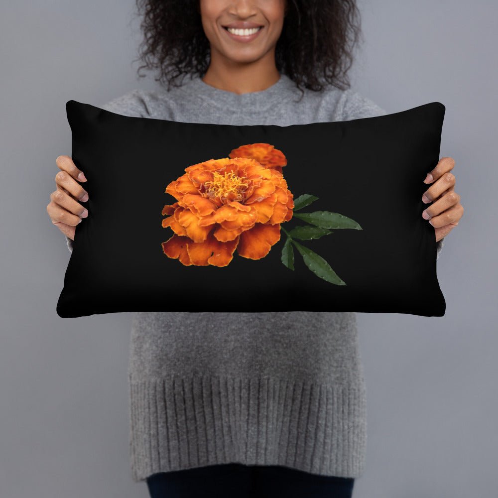 Orange Flower Pillow: Black decorative pillow with vibrant marigold design, held by person. Main Street Collective.
