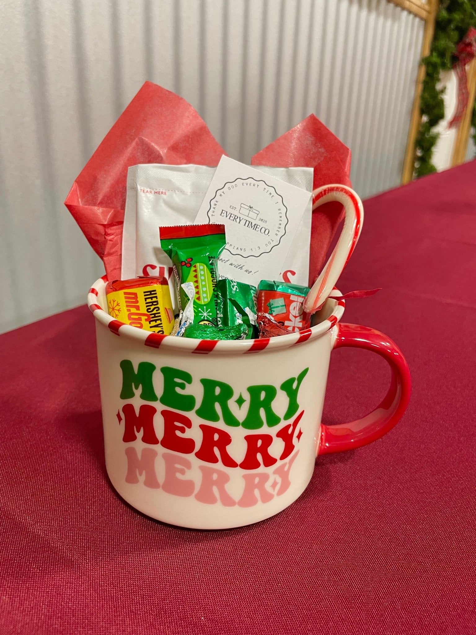 Merry Mug Gift Basket: Festive Christmas mug filled with candy, hot chocolate, and a peppermint spoon from Main Street Collective.
