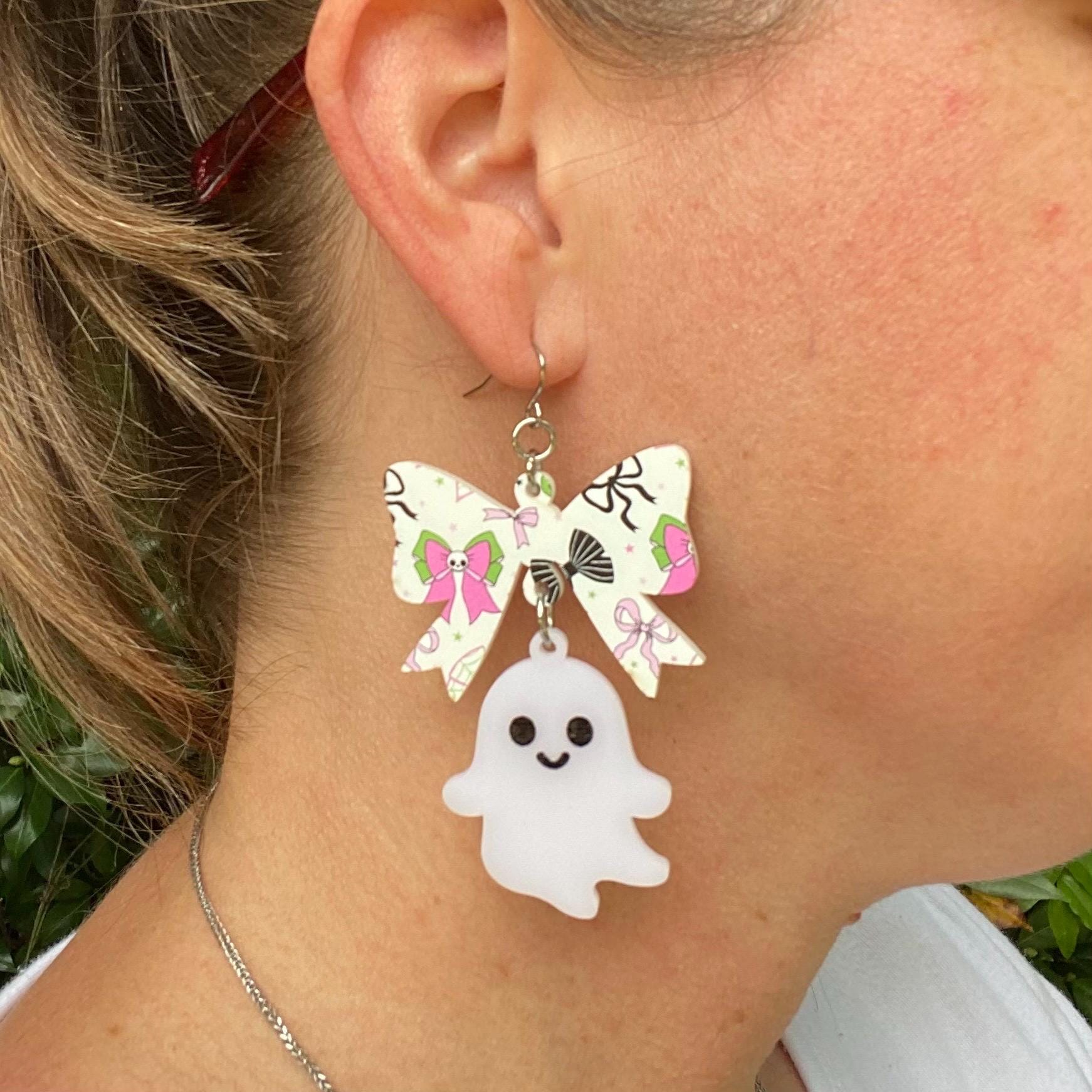 Ghost bow earrings: Halloween jewelry, handmade acrylic dangle earrings, woman wearing Main Street Collective.