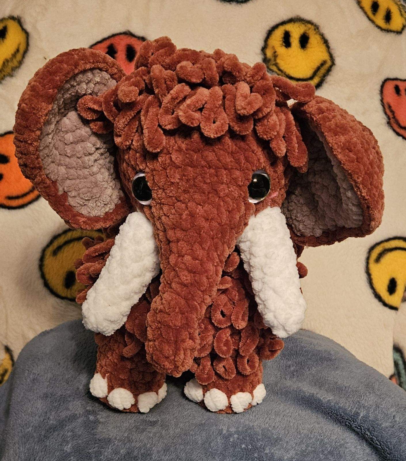 TULLY THE MAMMOTH Amigurumi by Main Street Collective: Brown crochet mammoth plush toy with white tusks and smiley face background.