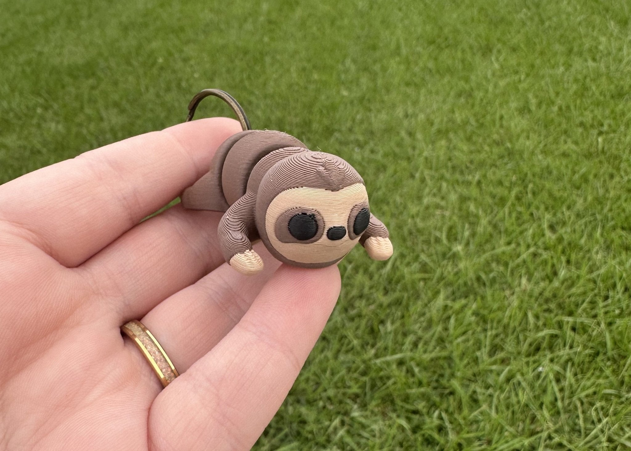 3D-printed sloth keychain held in hand, by Mushroom Lady Co. available at Main Street Collective.