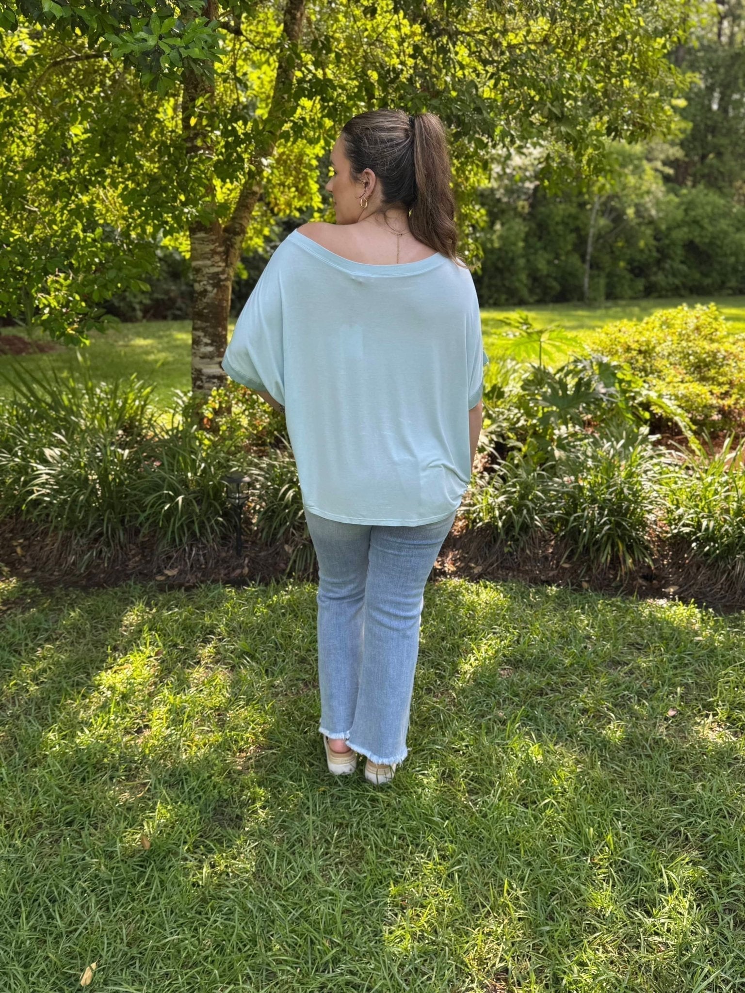 Light Blue Satin Top: Woman wearing Italian satin blouse by Main Street Collective in outdoor setting.