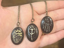 Image of all three oval relic pendant necklaces on a hand