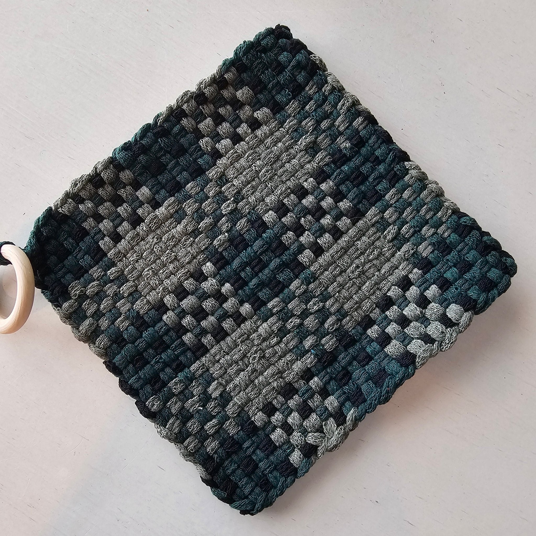 Handmade woven potholder: green and gray looped design with a wooden ring from Main Street Collective, Penelope's Potholders.