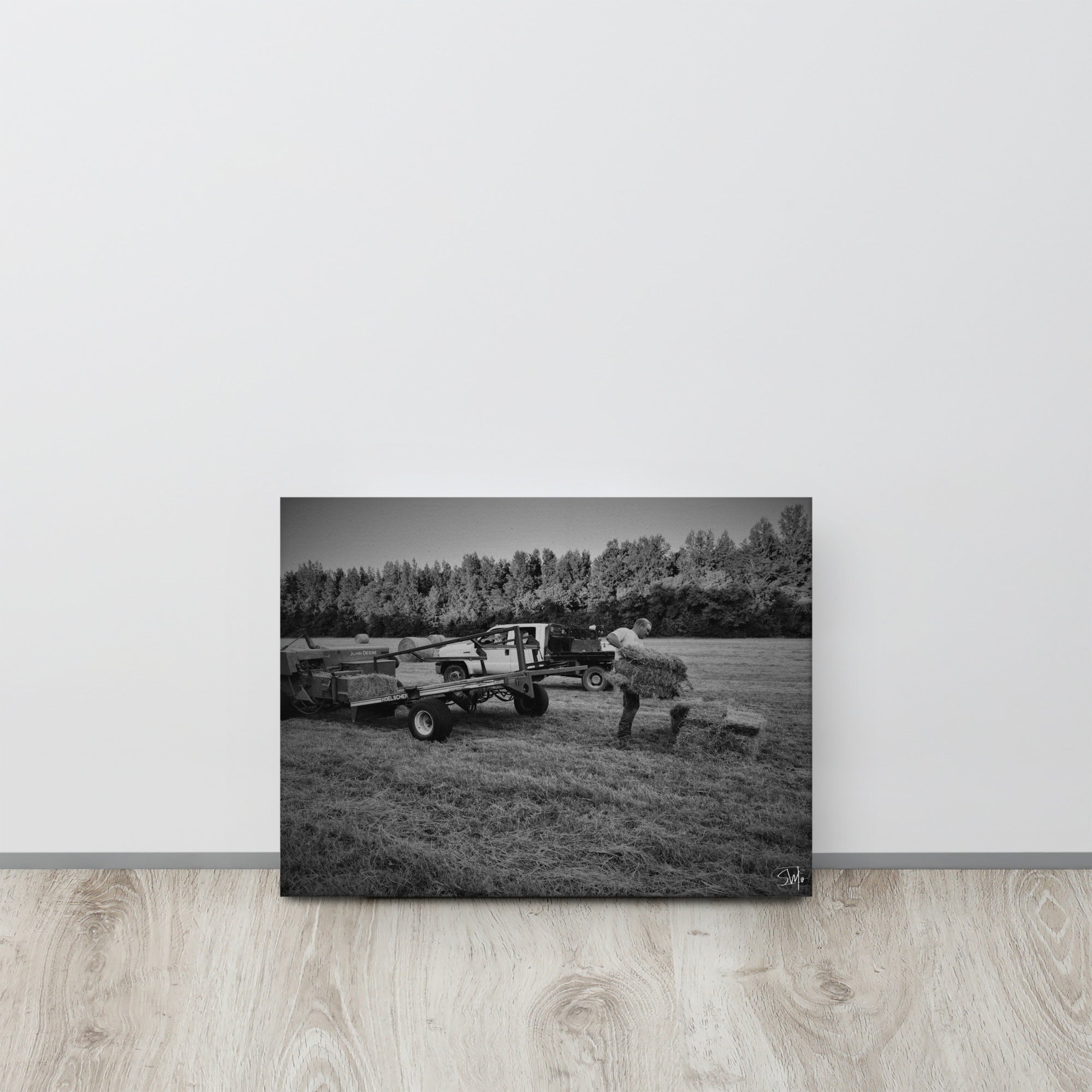 Black and white canvas art of a farmer loading hay bales in a rural scene.