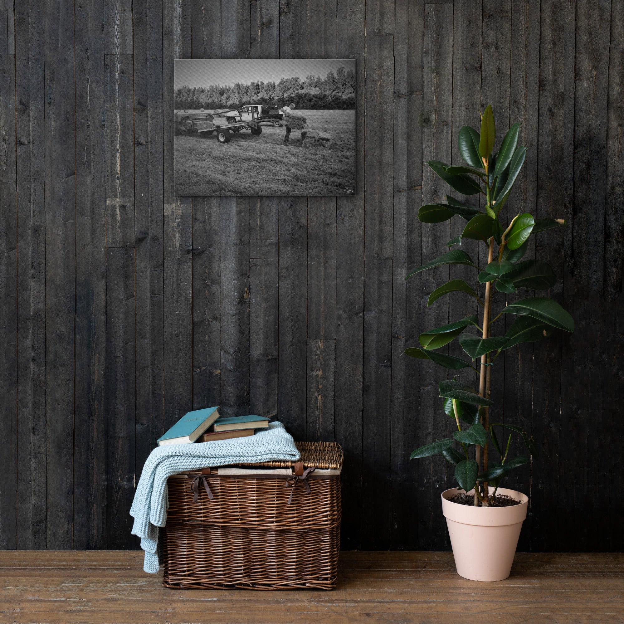 Hay Fever Canvas Art: Grayscale farm scene featuring hay bales, displayed above a wicker chest and potted plant.