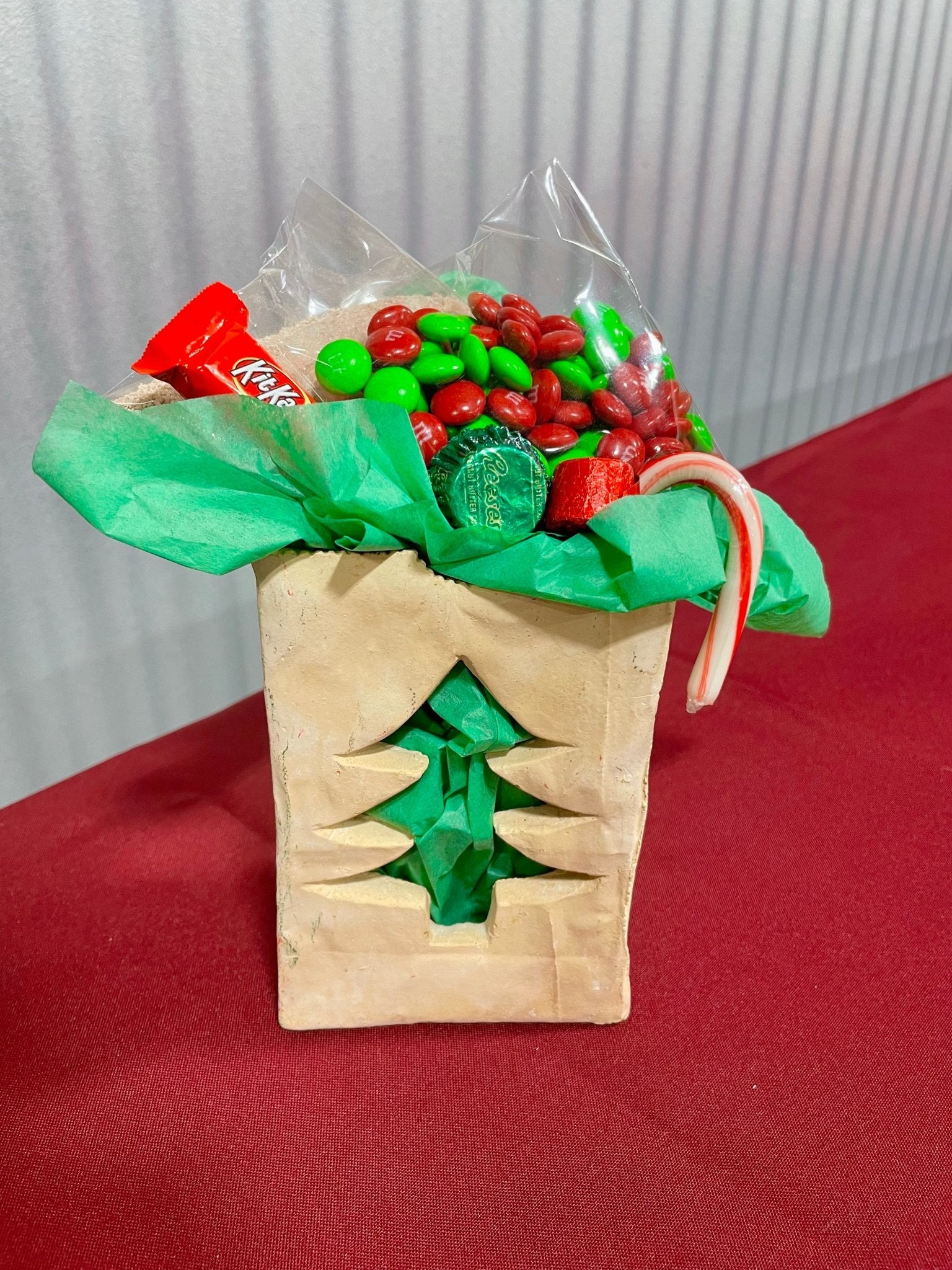 Ceramic Christmas tree paper bag with hot cocoa kit, M&Ms, candy cane, KitKat & Reese's cup. Main Street Collective family holiday treat.